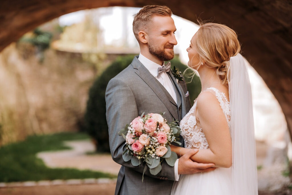 Ein verliebtes Brautpaar schaut sich tief in die Augen, während sie sich in einem romantischen Moment verlieren.