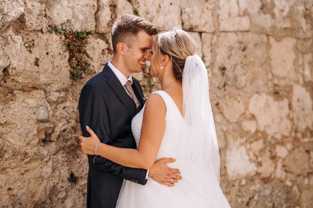 Die glückliche Braut und der Bräutigam stehen umarmend zusammen, strahlend vor Freude und Liebe an ihrem Hochzeitstag.